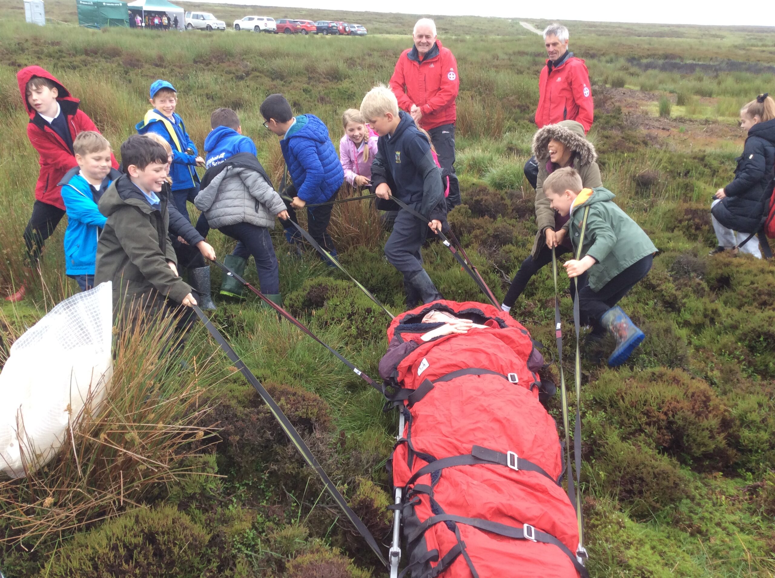 School children hauling a teacher to practice rescuing while on a school trip with Killinghall C.E