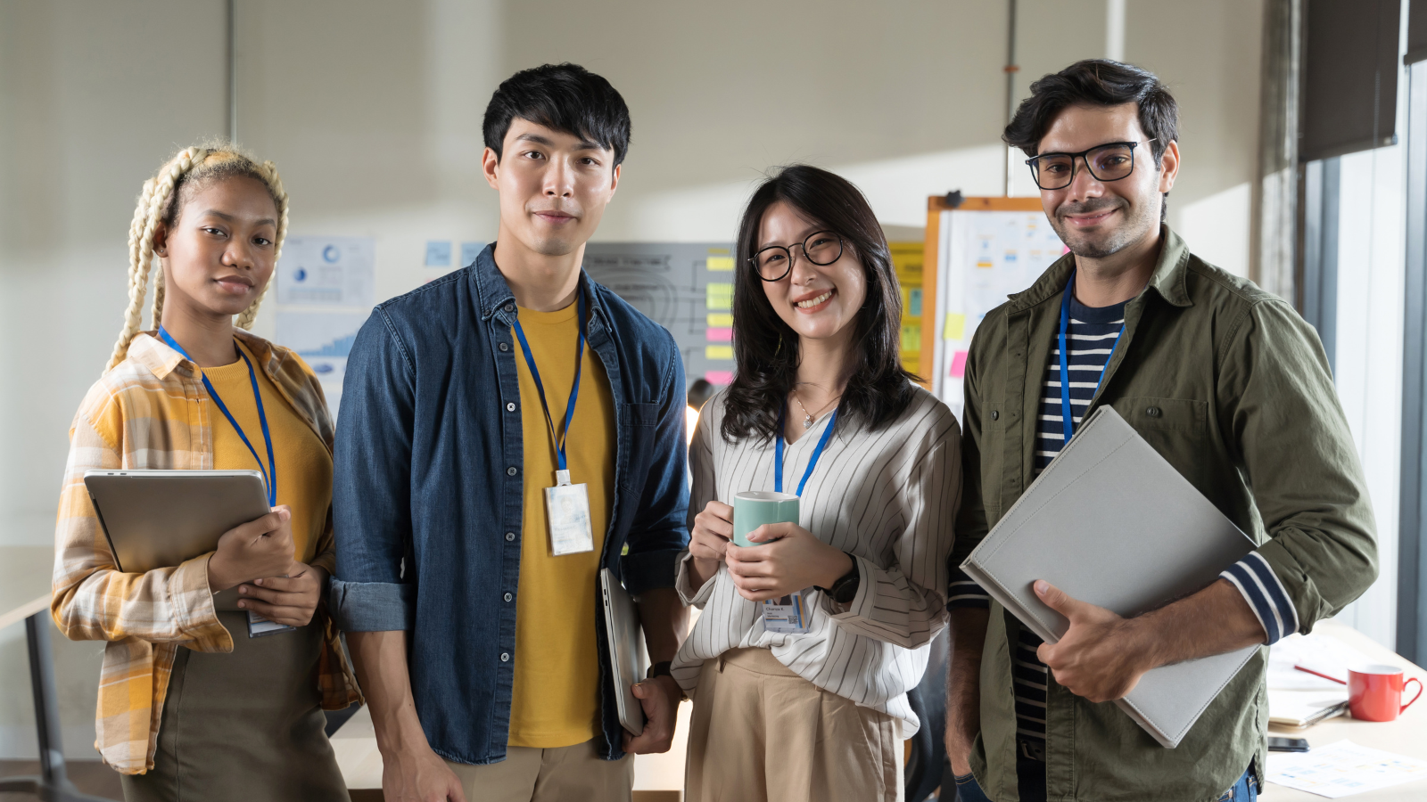 Group of two men and two women smiling directly at the camera, wearing work attire