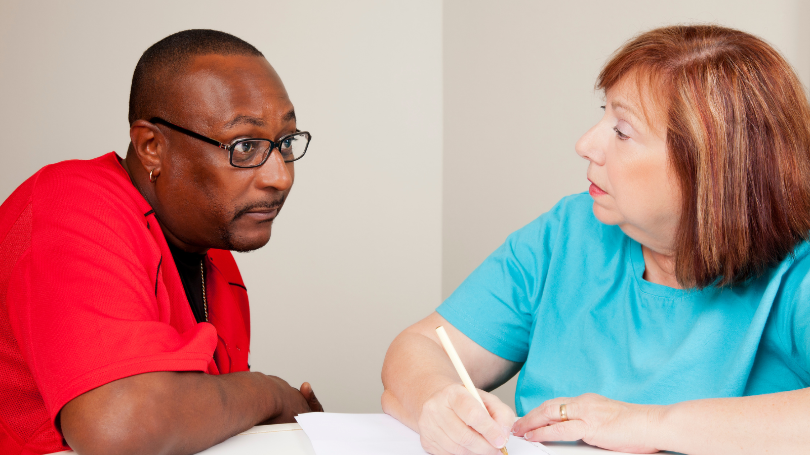 Social worker writing while talking to person - Help for all sponsored workers in Adult Social Care